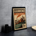 A vintage-style stamp depicting a cityscape with a bridge and industrial buildings, placed on a countertop next to some black camera lenses.