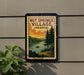 A vintage-style sign for Hot Springs Village, Arkansas, featuring a scenic landscape with pine trees, a lake, and a sunset.
