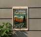 A sign for La Canada Flintridge, a scenic location in California, featuring a mountain landscape and a winding road.