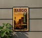 A framed poster of a cityscape with a sign for the Fargo, North Dakota theater, mounted on a wall.