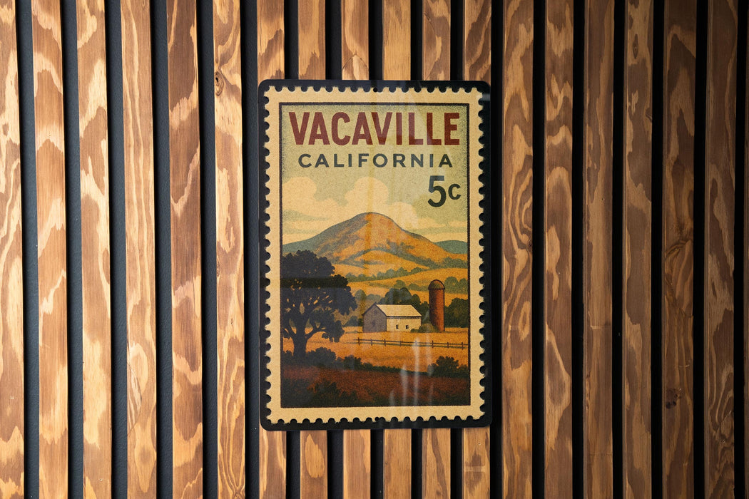A vintage California 5c postage stamp with a rural landscape and a barn, displayed on a wooden wall.