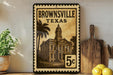 A framed vintage-style stamp depicting a building in Brownsville, Texas, with the text "Brownsville, TX" printed on it.