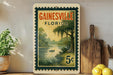 A vintage postage stamp from Florida, featuring a serene landscape with a river, palm trees, and a small boat, displayed on a shelf next to a wooden cutting board and some lemons.
