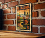 A vintage-style metal stamp depicting a cityscape with a clock tower, hanging on a brick wall.