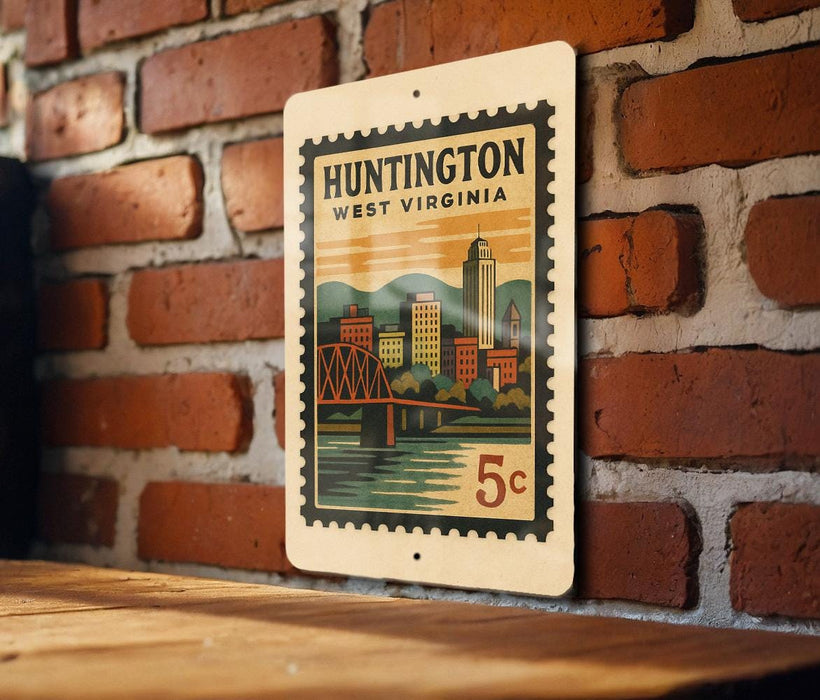 A vintage-style postage stamp from Huntington, West Virginia, featuring a cityscape and a bridge, is displayed on a brick wall.