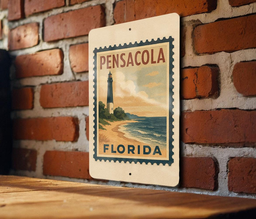 A vintage-style sign for Pensacola, Florida, featuring a lighthouse and beach scene, mounted on a brick wall.