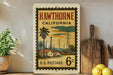 A vintage-style postage stamp from the United States, featuring an illustration of a small town in California with palm trees and power lines.