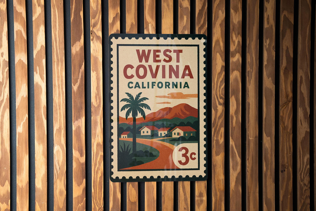 A vintage-style West Covina, California postage stamp is displayed on a wooden wall.
