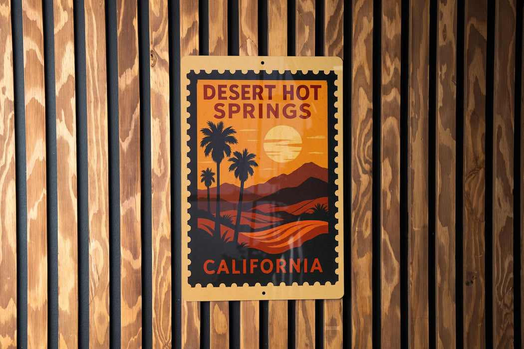 A poster of Desert Hot Springs, California, featuring palm trees and a sunset landscape, is displayed on a wooden wall.