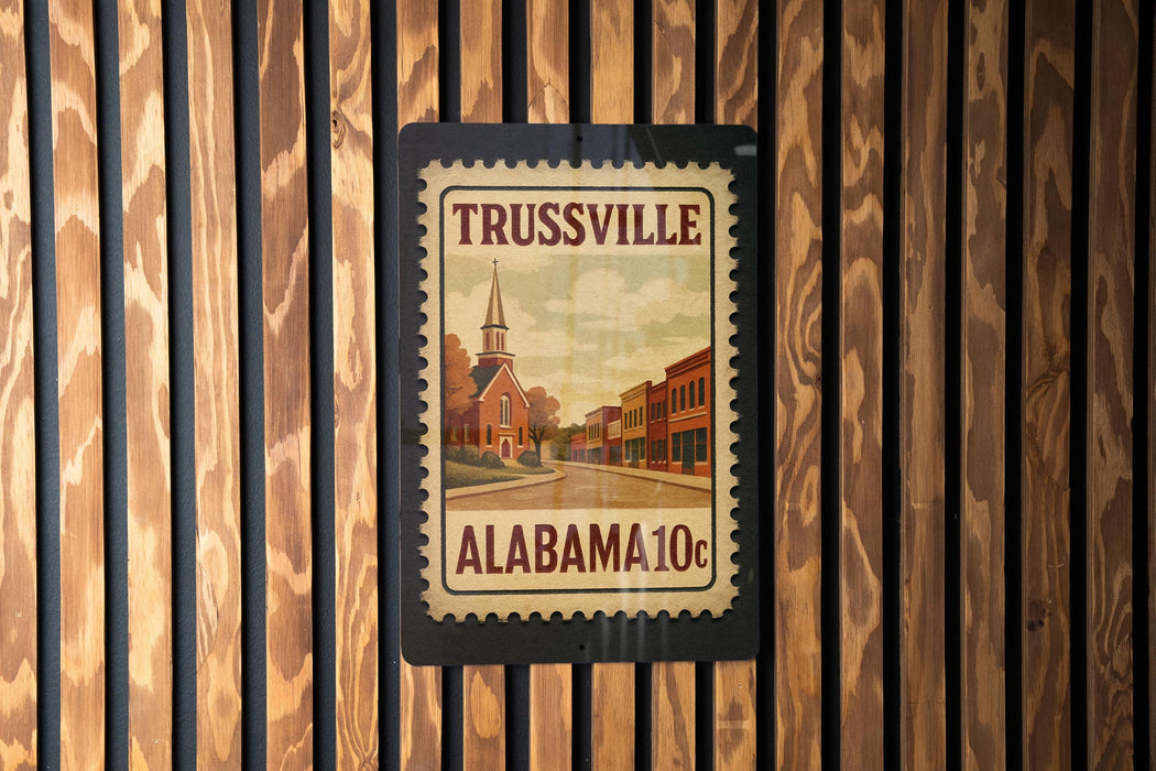 A framed poster of Trussville, Alabama, with a church and buildings depicted, is mounted on a wooden wall.