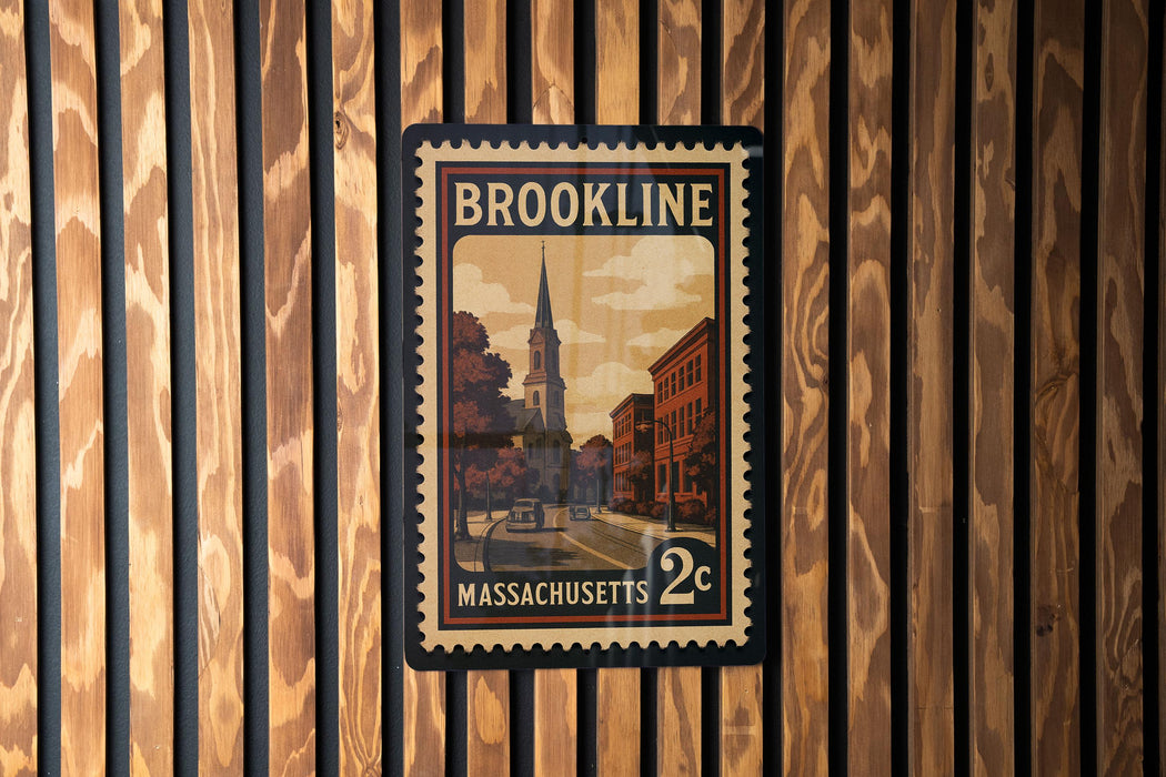 A vintage postage stamp from Massachusetts, featuring a church and a street scene, is displayed on a wooden wall.