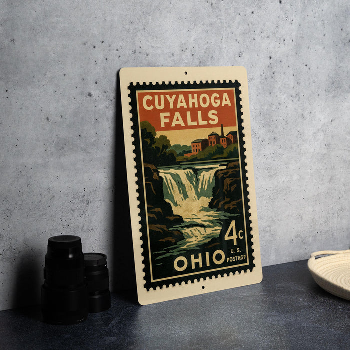 A vintage postage stamp depicting Cuyahoga Falls, Ohio, with a waterfall and surrounding landscape.