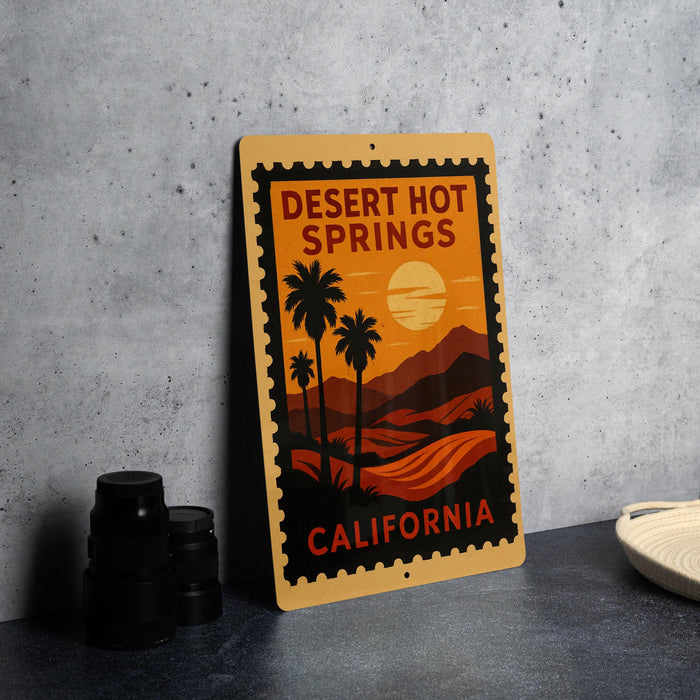A metal sign with a desert landscape and palm trees, featuring the text "DESERT HOT SPRINGS CALIFORNIA" on it, is displayed on a table.
