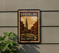 A vintage postage stamp from Massachusetts, featuring a church and a street scene, is displayed on a wall.