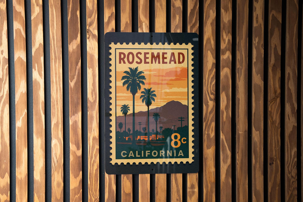 A vintage-style postage stamp from California, featuring a palm tree and sunset landscape, is displayed on a wooden wall.