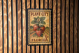 A vintage-style stamp or label with a strawberry plant and the text "PLANT CITY FLORIDA" printed on it, mounted on a wooden wall.