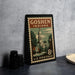 A vintage postage stamp from Goshen, Indiana, featuring a building and trees, placed on a countertop next to some black camera lenses.