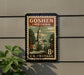 A postage stamp from Goshen, Indiana, featuring a clock tower and other architectural elements, mounted on a wall.