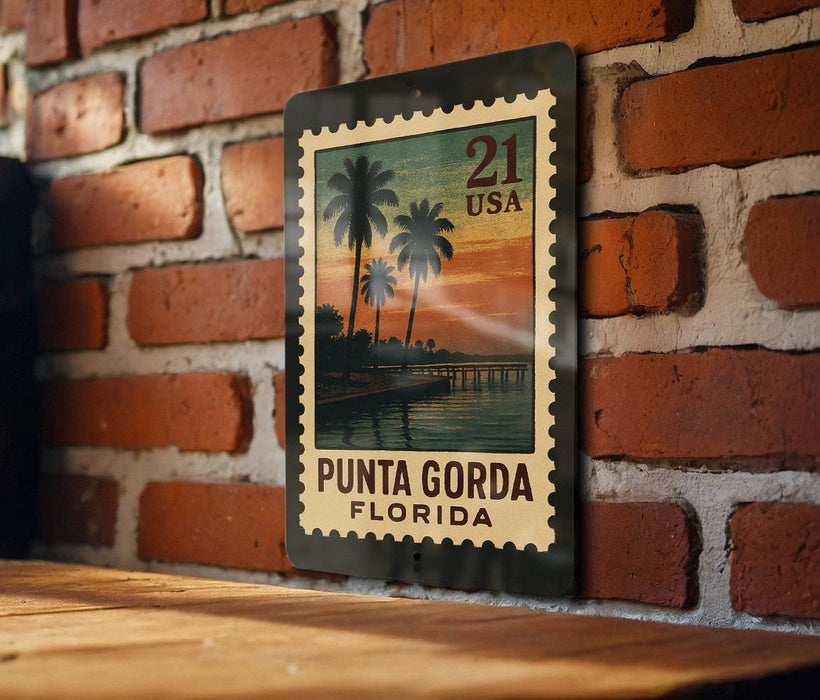 A metal stamp with a tropical beach scene, featuring palm trees and a sunset, is displayed on a brick wall.