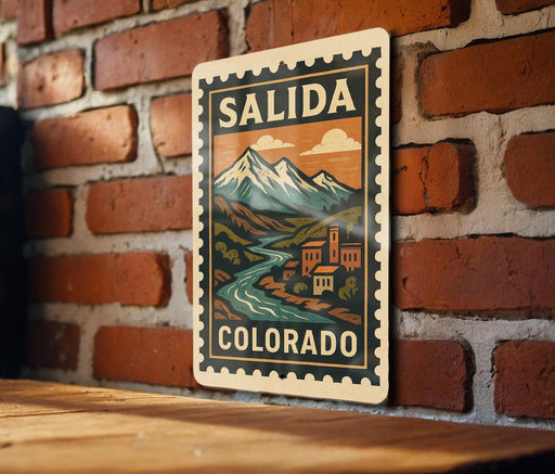 A metal sign with a mountain landscape and a river, mounted on a brick wall.