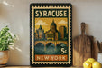A vintage postage stamp from New York, featuring a cityscape and a bridge, is displayed on a shelf next to a wooden cutting board and some lemons.