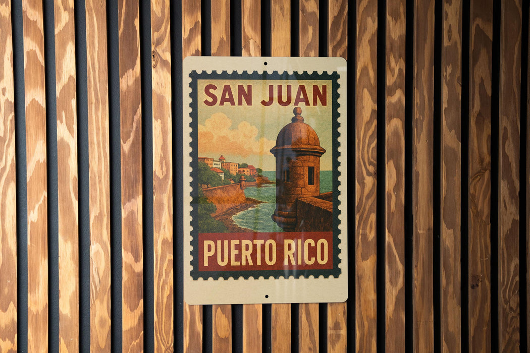 A vintage-style poster of the San Juan, Puerto Rico, featuring a castle-like structure and a body of water, mounted on a wooden wall.