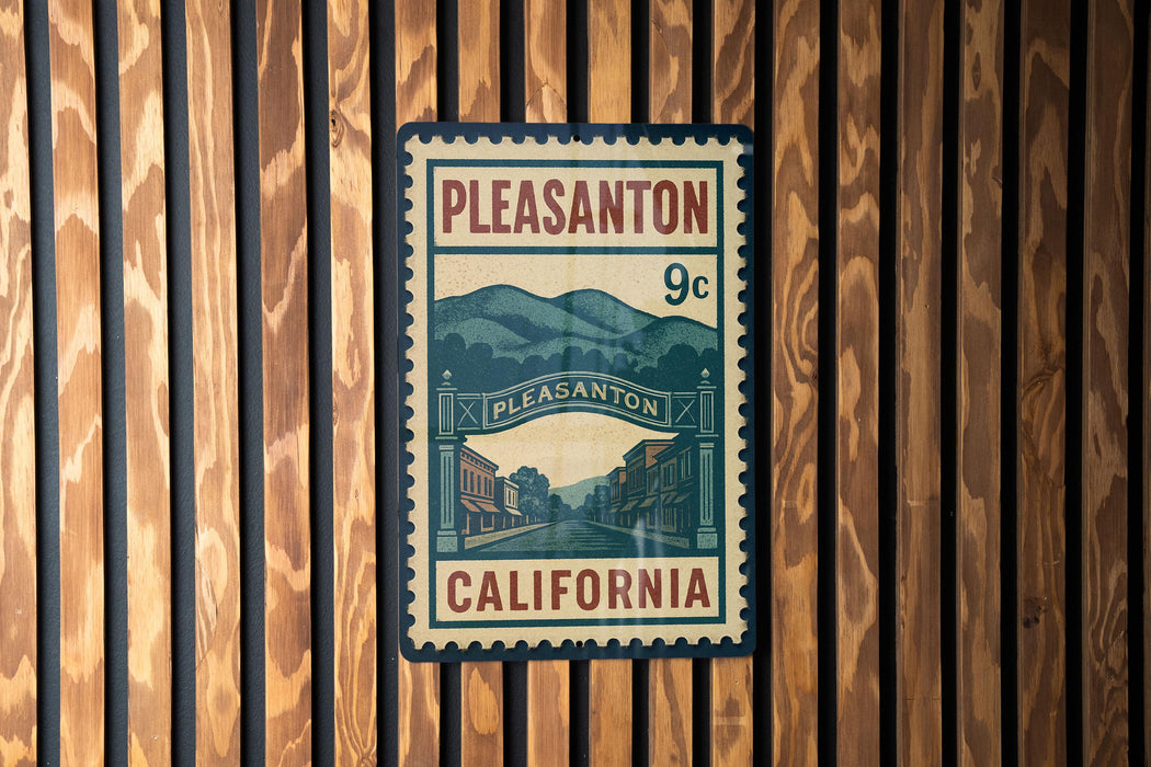 A vintage-style postage stamp from Pleasanton, California, featuring a street scene and mountains in the background.