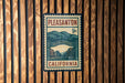 A vintage-style postage stamp from Pleasanton, California, featuring a street scene and mountains in the background.