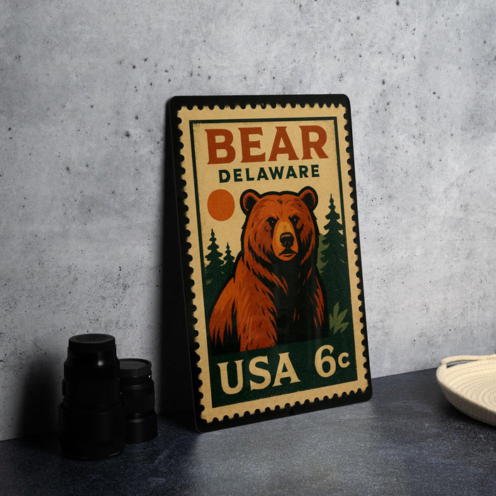A vintage-style metal stamp featuring a bear on a forest scene, with the text "BEAR DELAWARE USA 6c" printed on it.