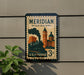 A vintage-style postage stamp from Meridian, Mississippi, featuring a steam locomotive and buildings, mounted on a wall.