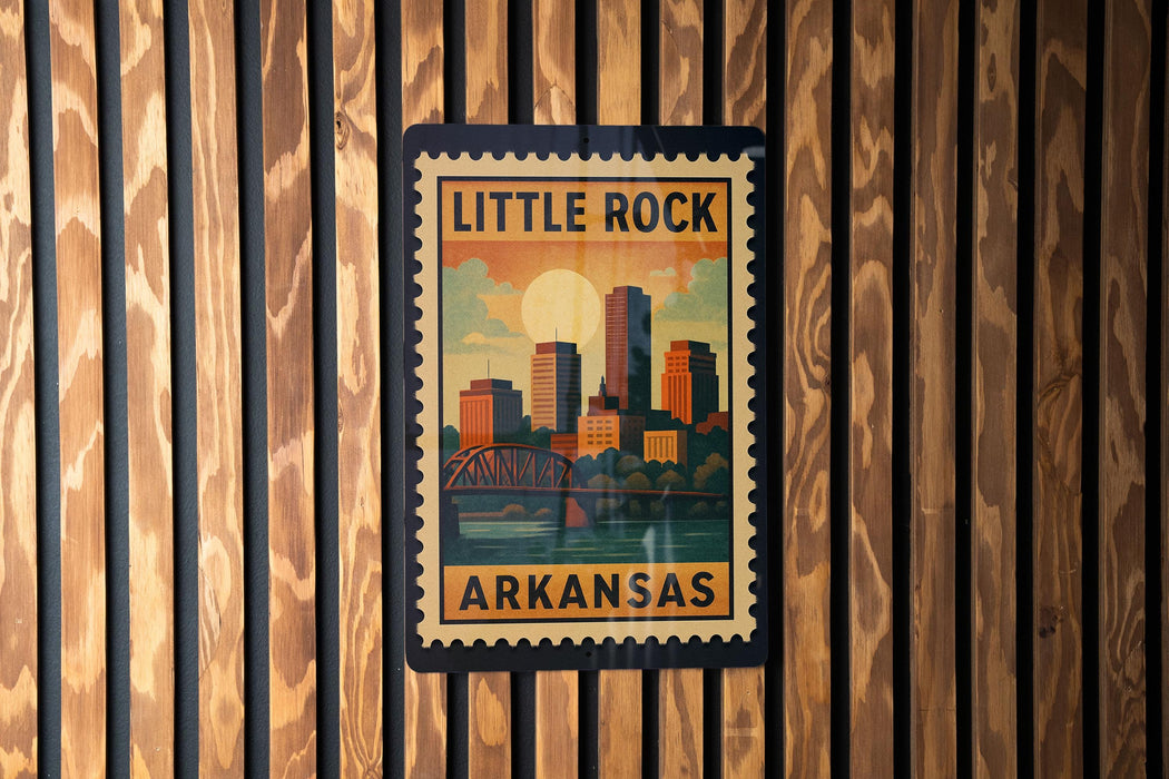 A framed poster of Little Rock, Arkansas, featuring a cityscape and a bridge, is displayed on a wooden wall.