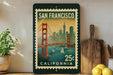 A framed vintage postage stamp depicting the Golden Gate Bridge in San Francisco, California, with the text "SAN FRANCISCO" and "25¢ CALIFORNIA" printed on it.