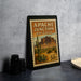 A framed vintage postage stamp depicting the Apache Junction, Arizona, with a desert landscape and cacti.