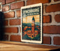 A vintage-style postage stamp depicting the city of Lynchburg, Virginia, with a clock tower and other buildings.