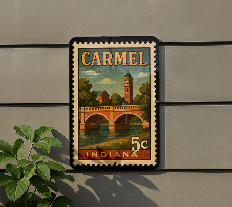 A vintage postage stamp from Indiana featuring a bridge and a clock tower, mounted on a wall next to a plant.