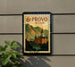 A vintage-style poster of the University of Utah, featuring a castle and mountains, is displayed on a wall.