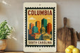 A framed poster of the city of Columbia, South Carolina, featuring a colorful illustration of the city skyline.