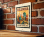 A metal sign with a colorful illustration of a city skyline and the text "COLUMBIA SOUTH CAROLINA" is displayed on a brick wall.