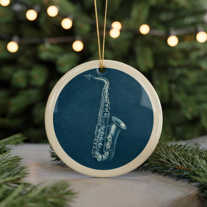 A blue ceramic ornament with a white border, featuring a detailed illustration of a saxophone on a dark background.