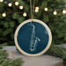 A blue ceramic ornament with a white border, featuring a detailed illustration of a saxophone on a dark background.