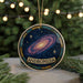 A circular ornament with a galaxy design and the word "ANDROMEDA" written on it, hanging from a string.