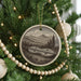 A Christmas tree decorated with ornaments, including a circular ornament featuring a musical instrument and a landscape scene.
