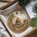 A round ornament with the word "ARCHITECT" on it, featuring a building and architectural tools, is displayed in a box with pine branches.