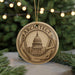 A circular ornament with the word "ARCHITECT" on it, featuring an illustration of a building and architectural tools, such as a compass and ruler, against a blurred background of a Christmas tree.