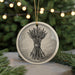 A round ornament with a black and white illustration of a bundle of arrows on it, hanging from a string.