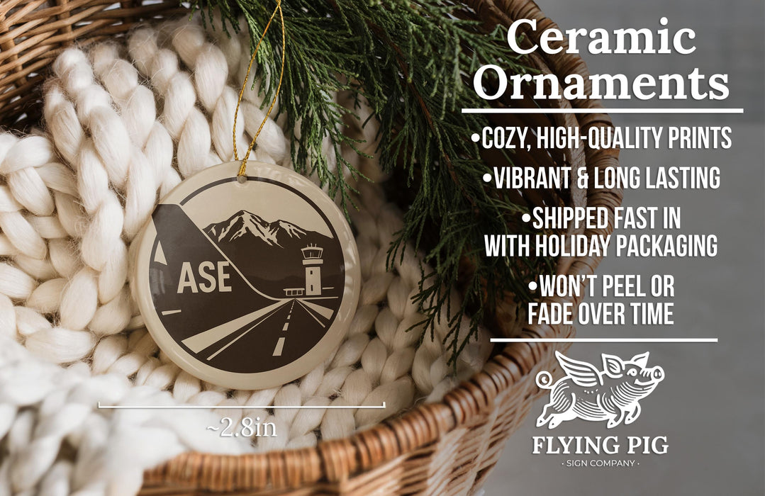 Ceramic ornaments, featuring a ceramic ornament with a mountain and airplane design, hanging in a wicker basket.