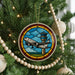 A Christmas tree decorated with ornaments, including a circular ornament featuring a stained glass image of an airplane on an airport control tower.