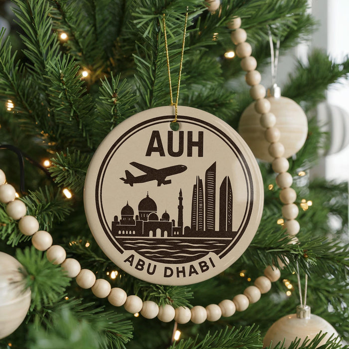 A Christmas tree decorated with ornaments, including a circular ornament with a graphic of Abu Dhabi skyline and the text "AUH" and "ABU DHABI".