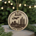 A circular ornament with a silhouette of a city skyline and a plane, along with the text "AUH ABU DHABI" on it, is displayed on a Christmas tree.
