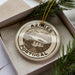 A circular ornament with the text "AZORES PORTUGAL" printed on it, surrounded by a decorative border and a pine branch.
